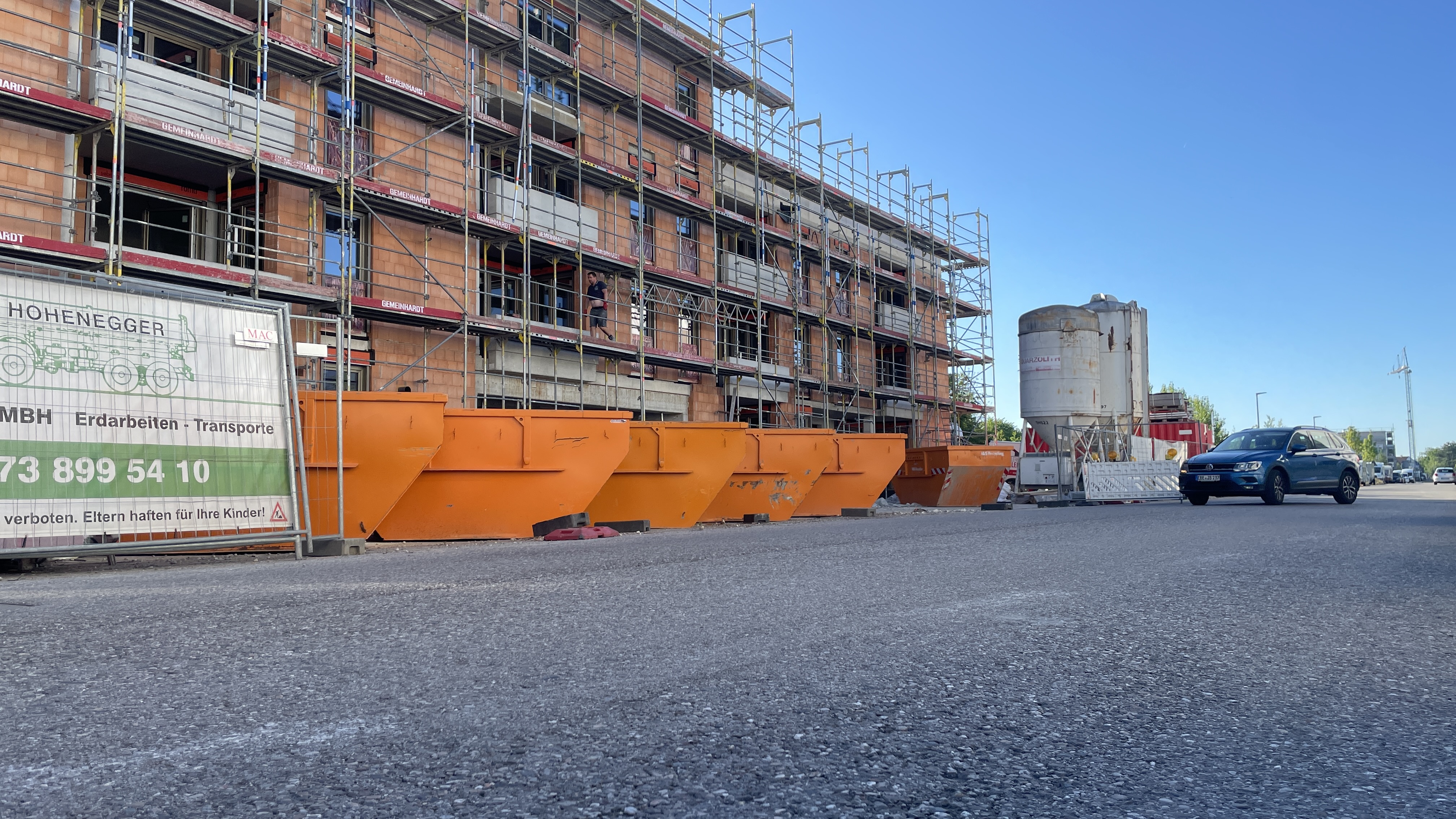 Reihe orangefarbener Container auf einer Baustelle mit Gerüst