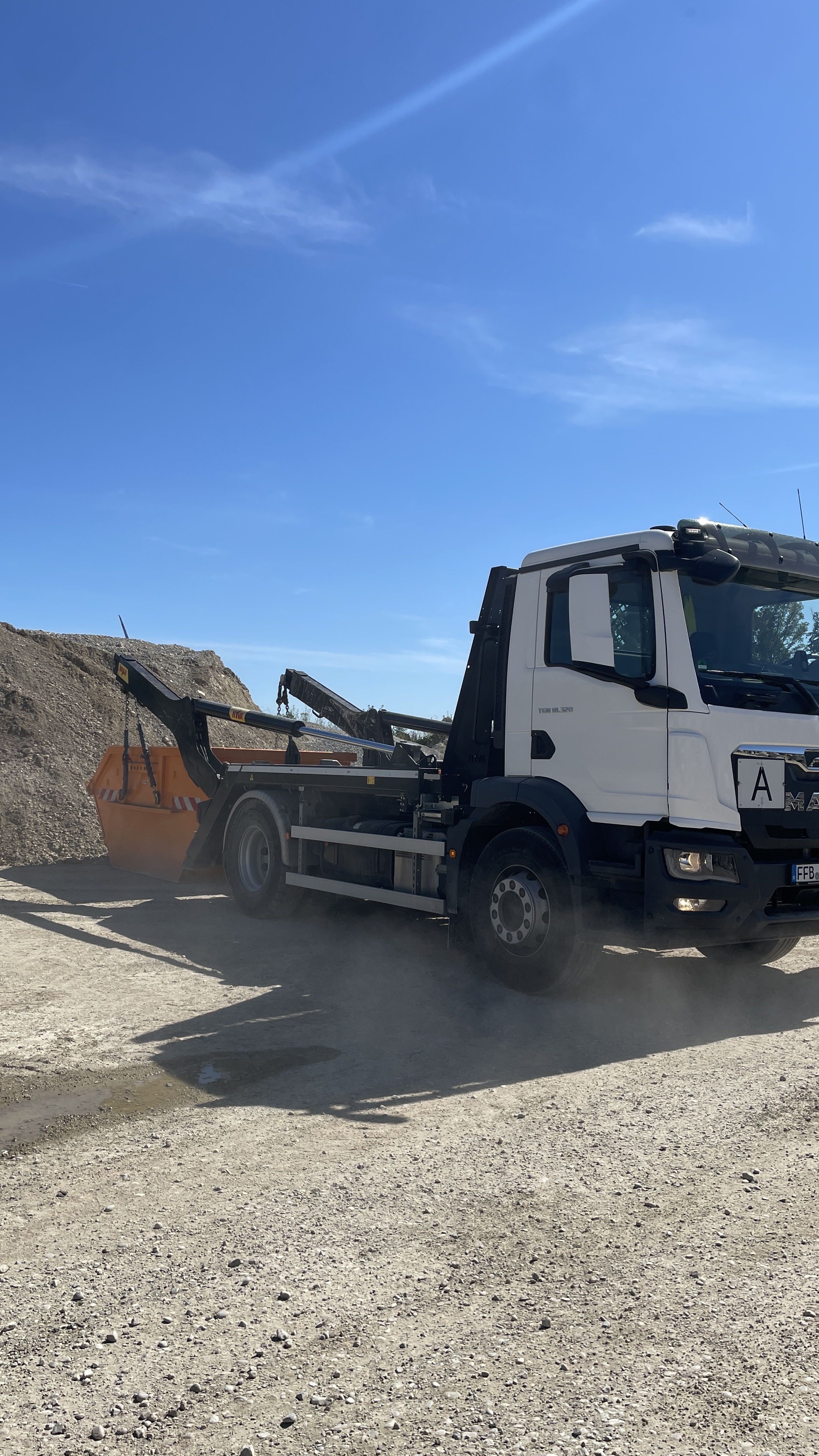 Weißer MAN Absetzkipper mit orangem Container auf einer Baustelle